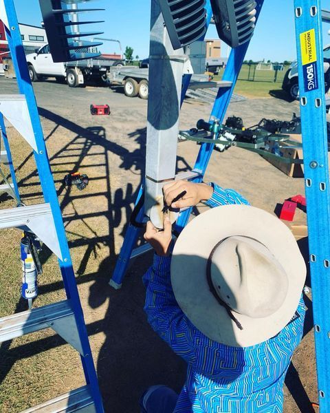 A Man Wearing a Hat Is Working on A Ladder — Paton's Electrical Services in Pialba, QLD