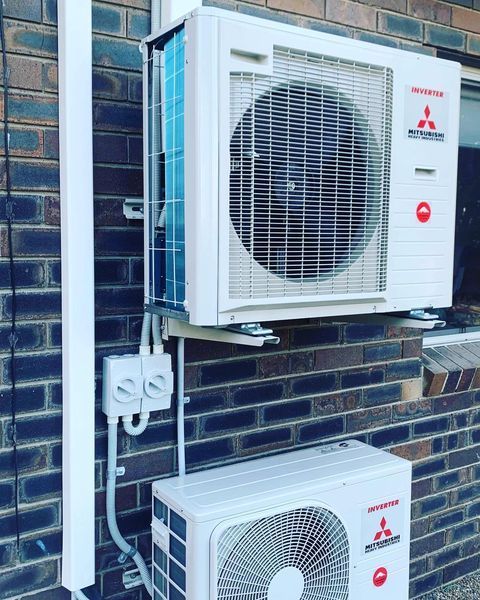 A Mitsubishi Air Conditioner Is Mounted on A Brick Wall — Paton's Electrical Services in Craignish, QLD