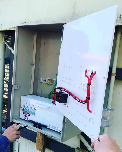 A Person Is Working on An Electrical Box with The Door Open — Paton's Electrical Services in Urraween, QLD
