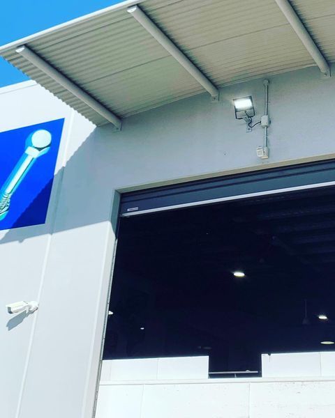 A White Building with A Blue Sign on The Side of It — Paton's Electrical Services in Torquay, QLD