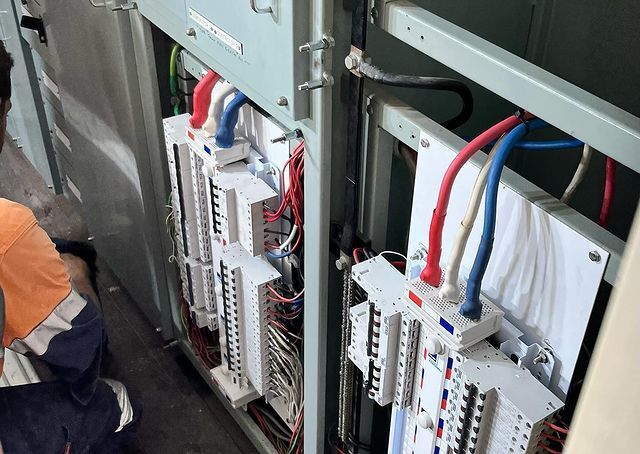A Man Is Kneeling Down In Front Of A Electrical Panel — Paton's Electrical Services in Craignish, QLD