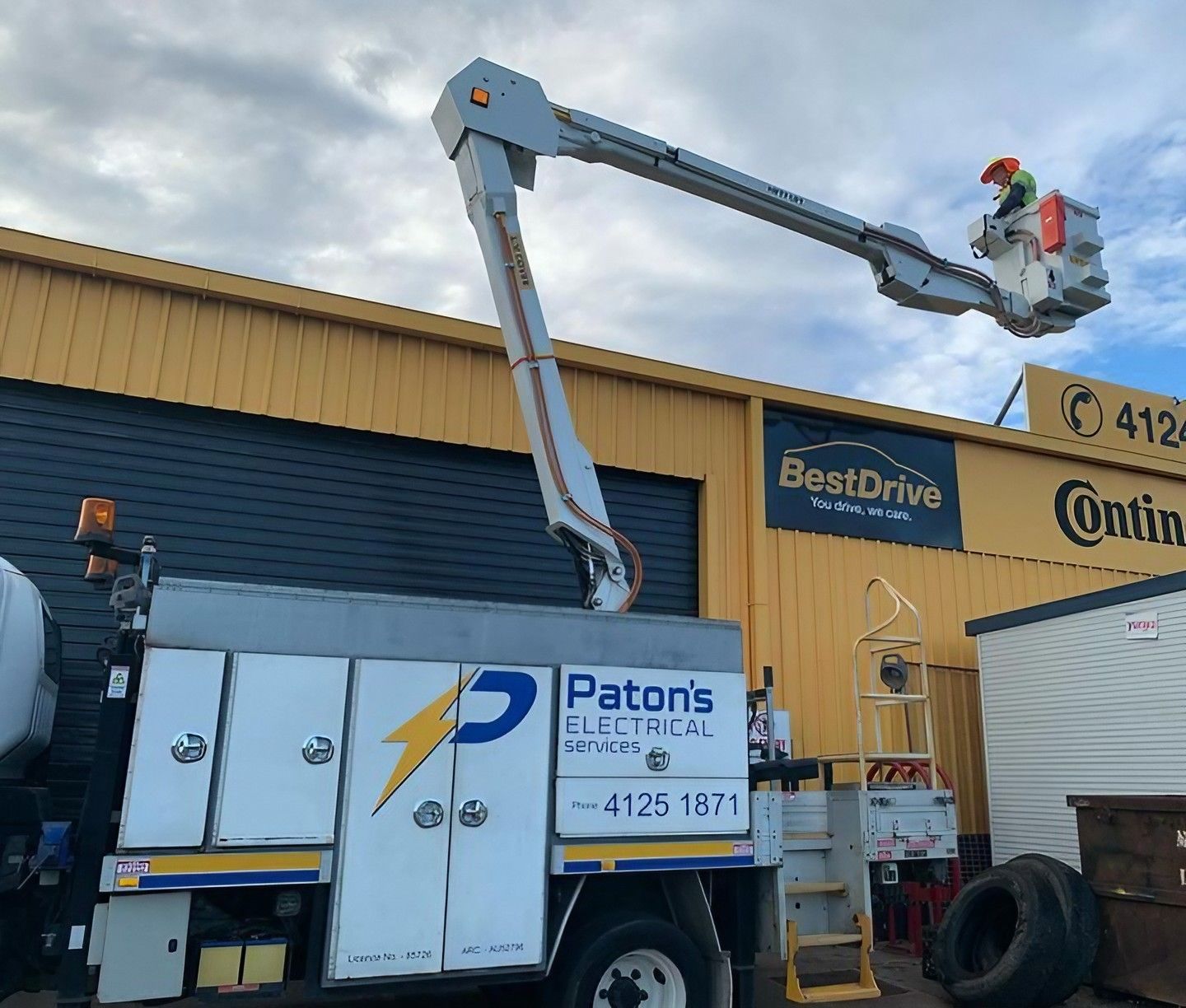 A Paton's Electrical Crane is Parked in Front of a Building — Paton's Electrical Services in Craignish, QLD
