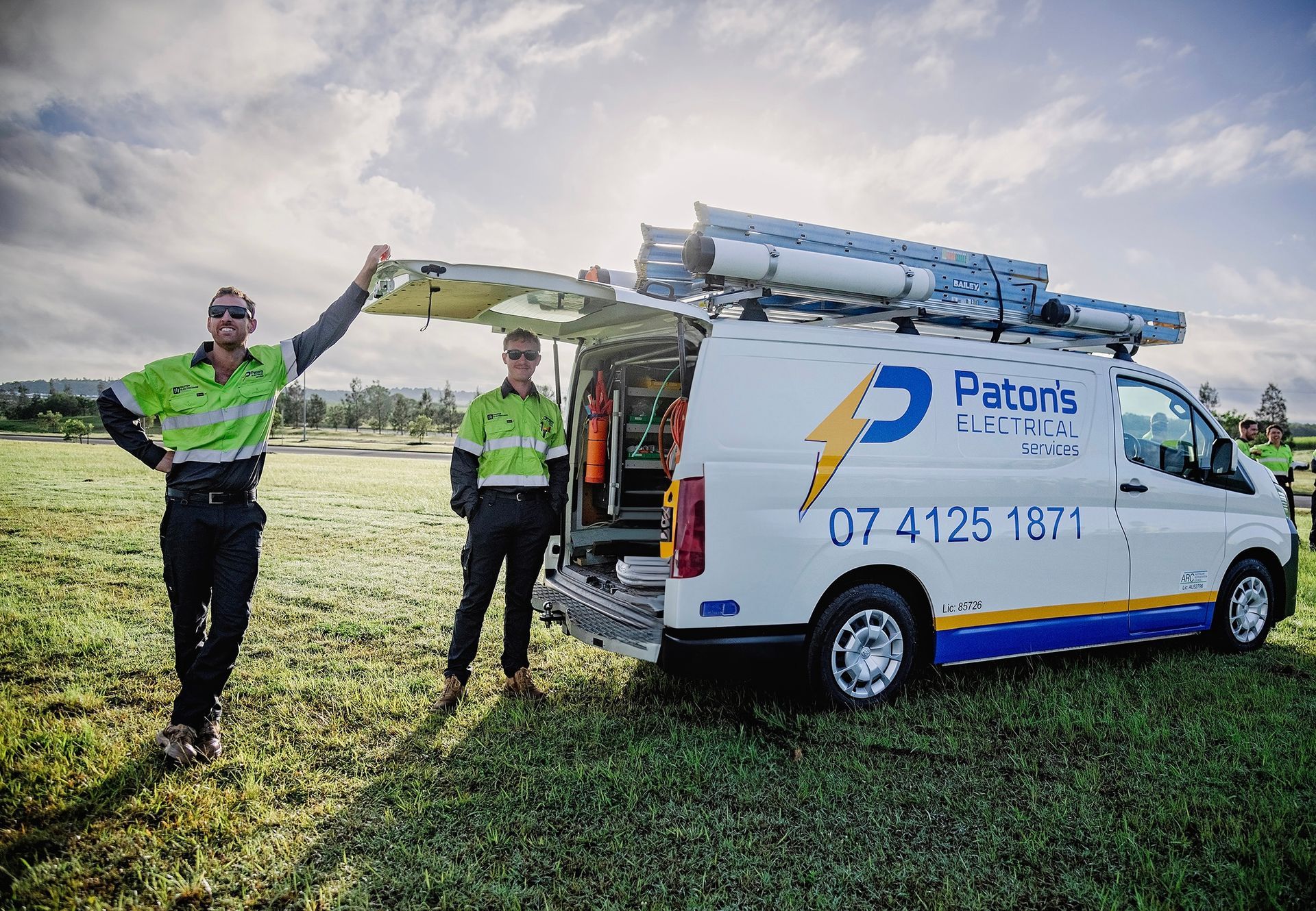 Two electricians beside a white van with