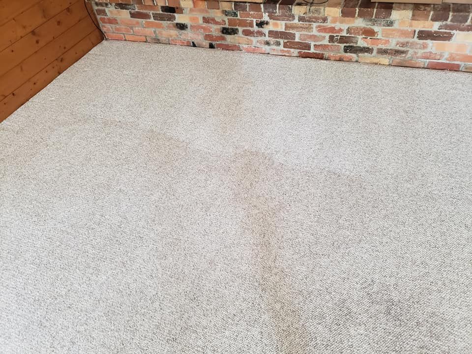 Light-colored speckled patio flooring with a vertical dark stain running through the center, adjacent to a brick wall.