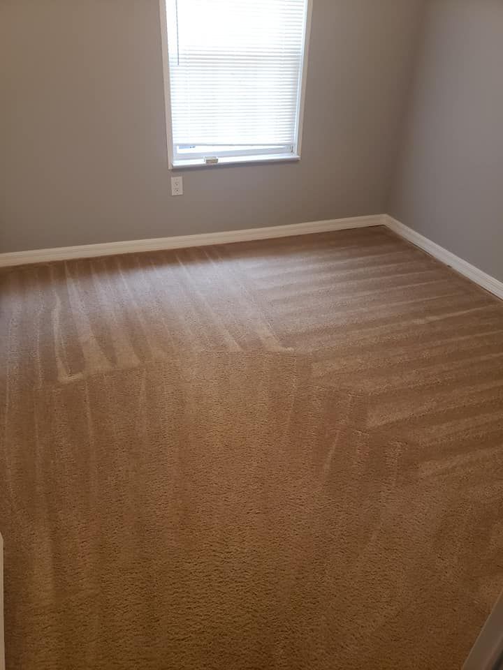 A clean, carpeted room with light gray walls and a single window with white blinds.