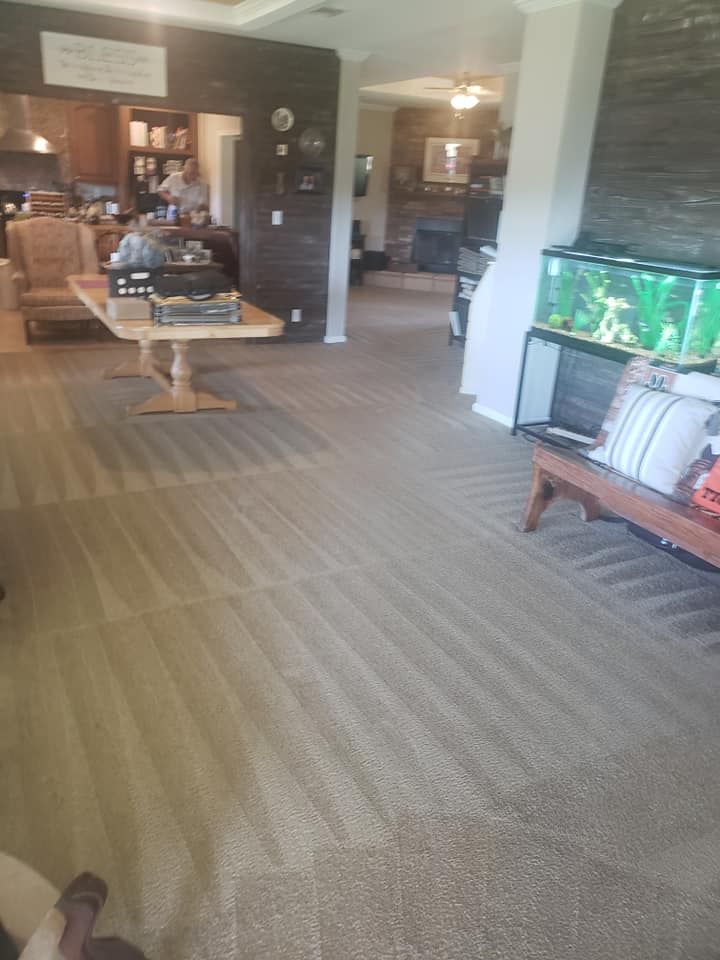 An open-concept living area with carpeted floors, a dining table in the background, and a fish tank on a wooden bench.