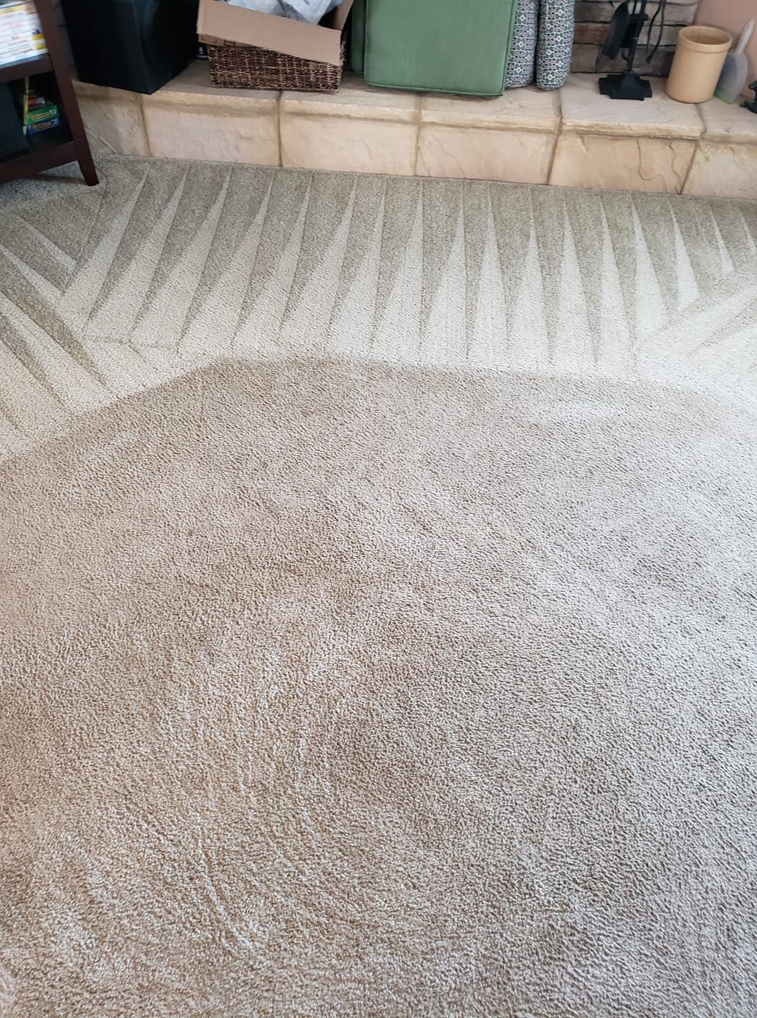 A freshly vacuumed beige carpet showing prominent diagonal cleaning lines leading toward a stone fireplace hearth.
