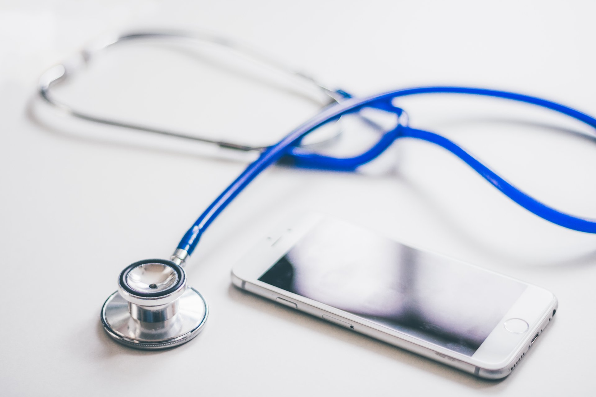 A stethoscope is sitting next to a cell phone on a table.