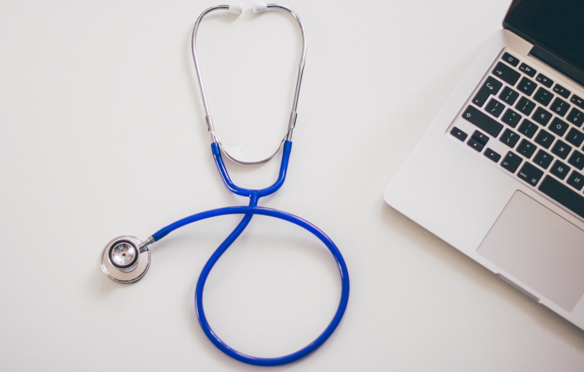 A stethoscope is sitting next to a laptop on a table.