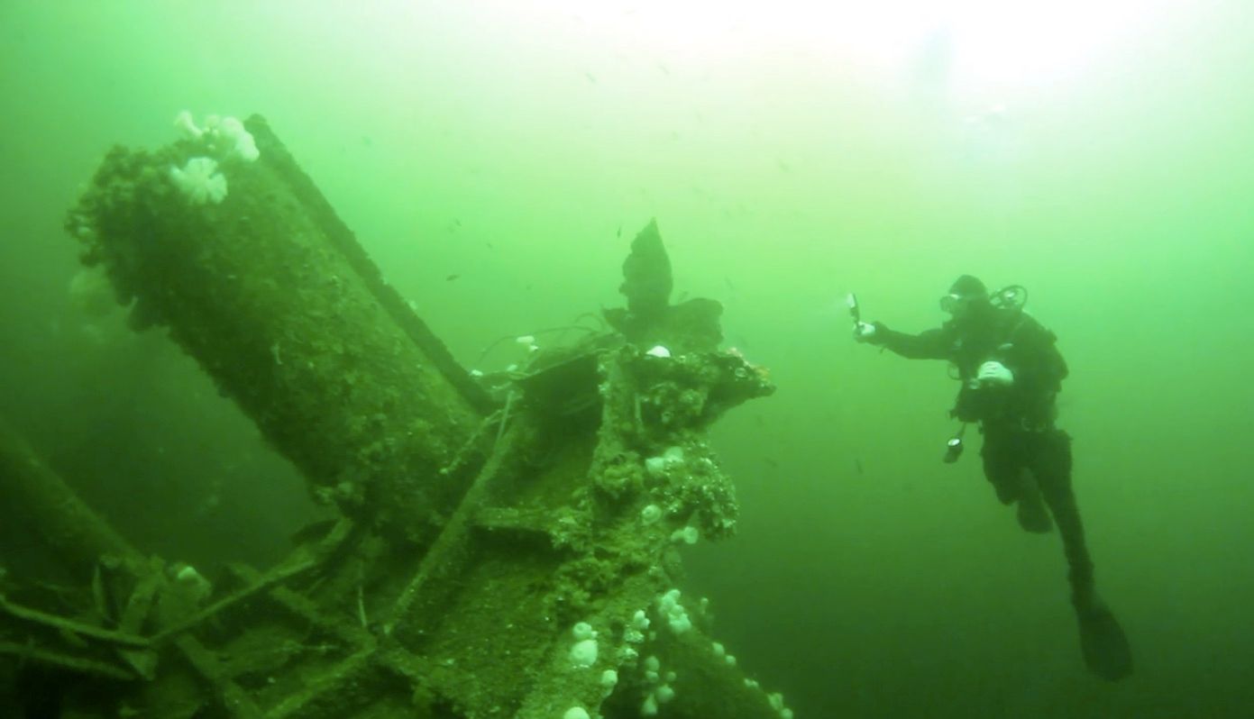 A scuba diver is swimming near a large object near Woods End Landing in Bamfield BC