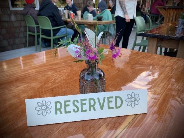 A vase of flowers sits on a table next to a reserved sign