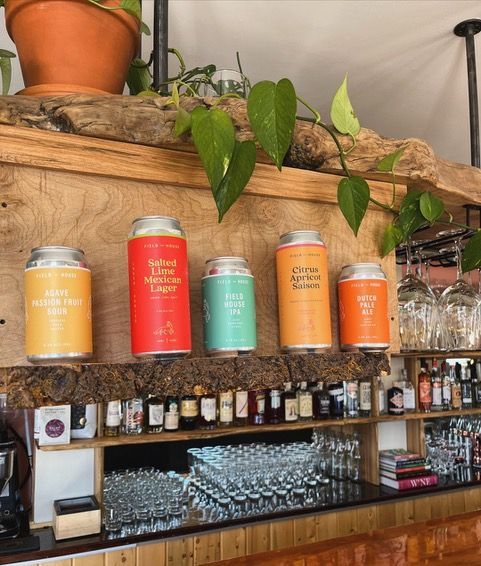 Several cans of beer are lined up on a wooden shelf