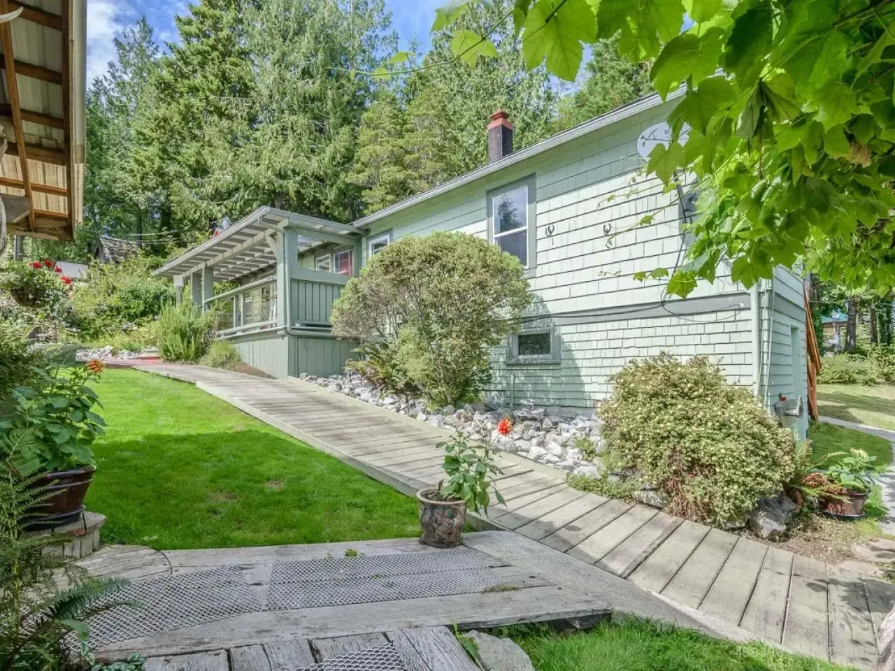 A house with a walkway leading to it is surrounded by trees and grass.