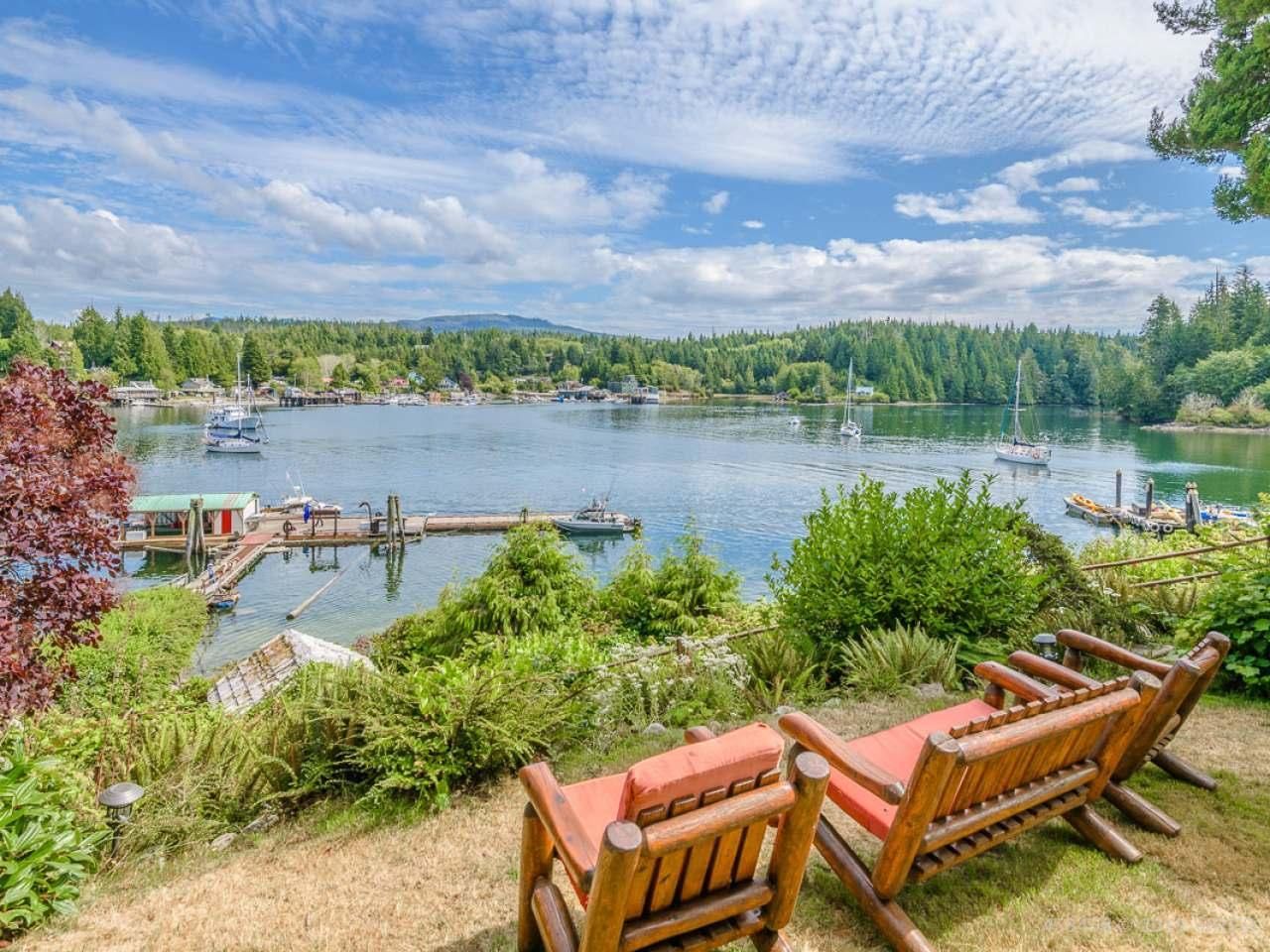 A couple of chairs sitting on top of a lush green hill overlooking a lake.
