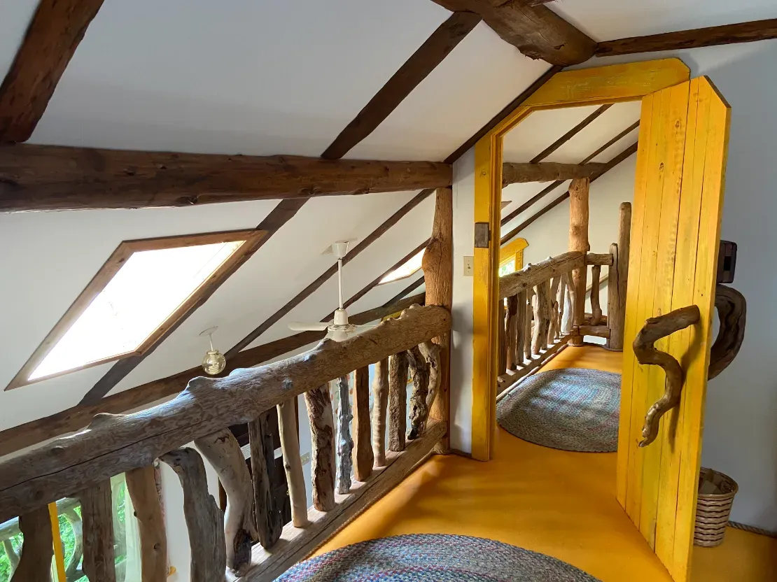 A hallway with a wooden railing and a yellow door