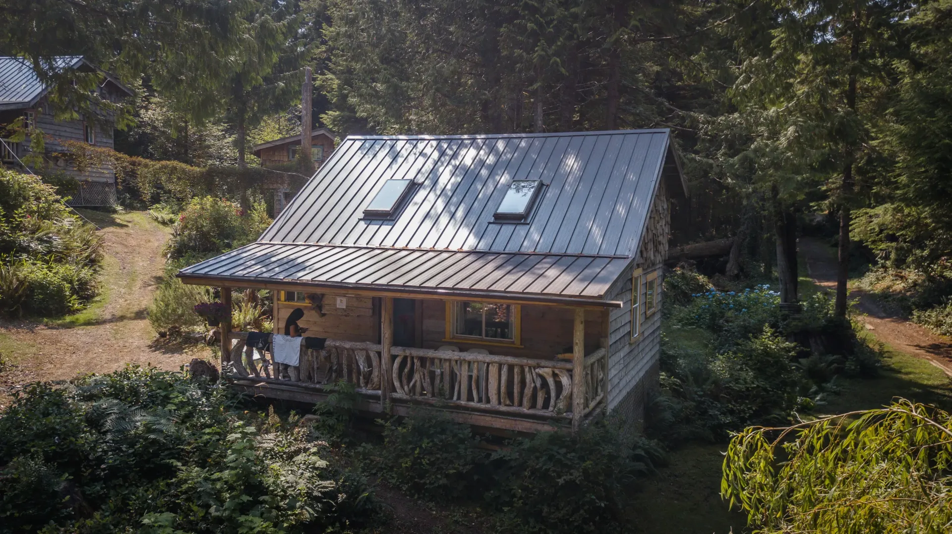 An aerial view of a small cabin in the middle of a forest.