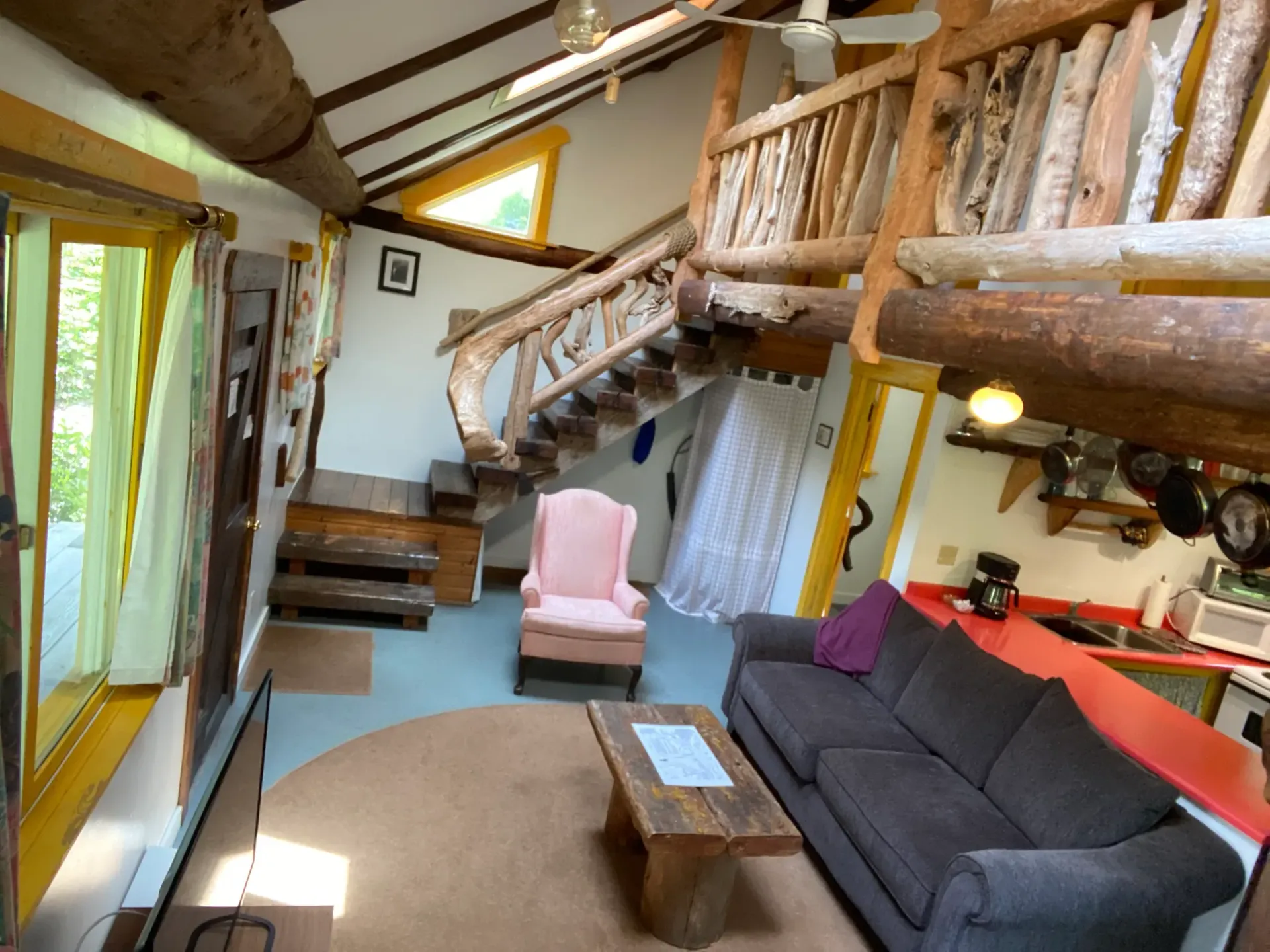 A living room with a couch , chair , coffee table and stairs