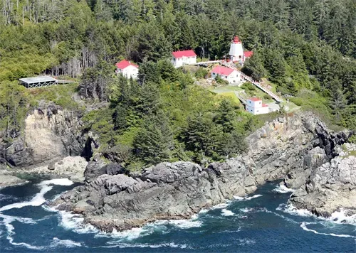 An aerial view of a lighthouse on a cliff overlooking the ocean.