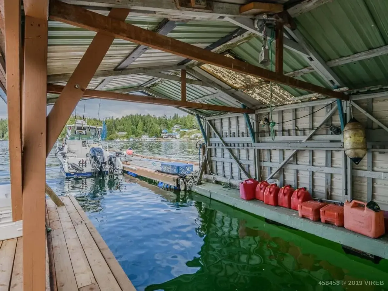 A boat is docked in a covered area next to a body of water.