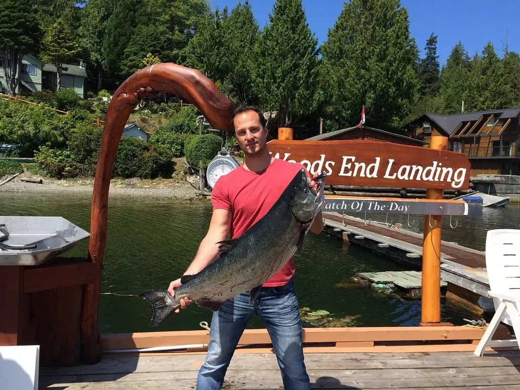 A man is standing on a dock holding a large fish.