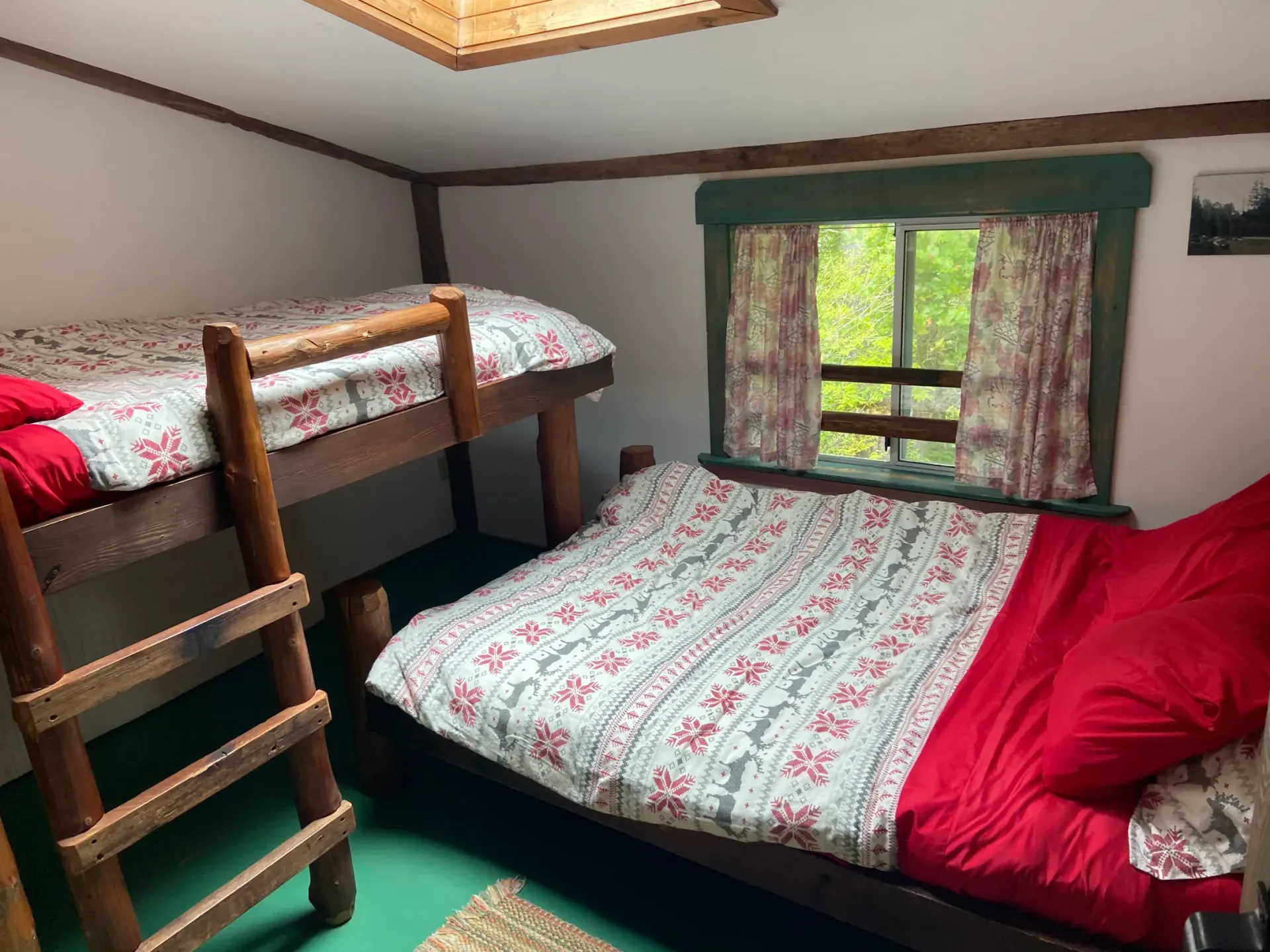 A bedroom with two bunk beds and a bed with red sheets.