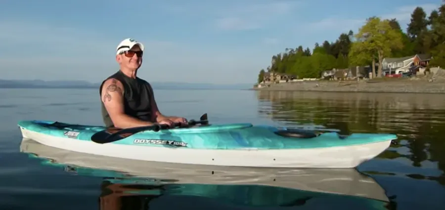 A man is sitting in a kayak on a lake.