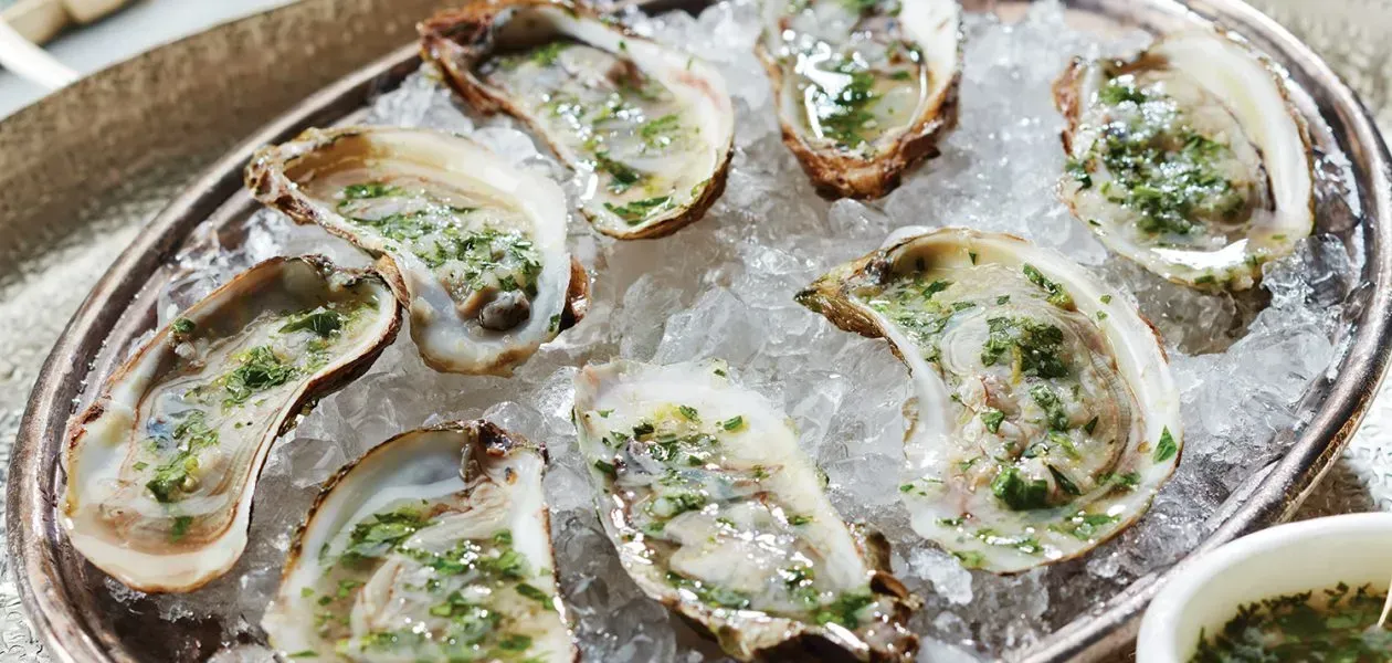 A plate of oysters on ice on a table.