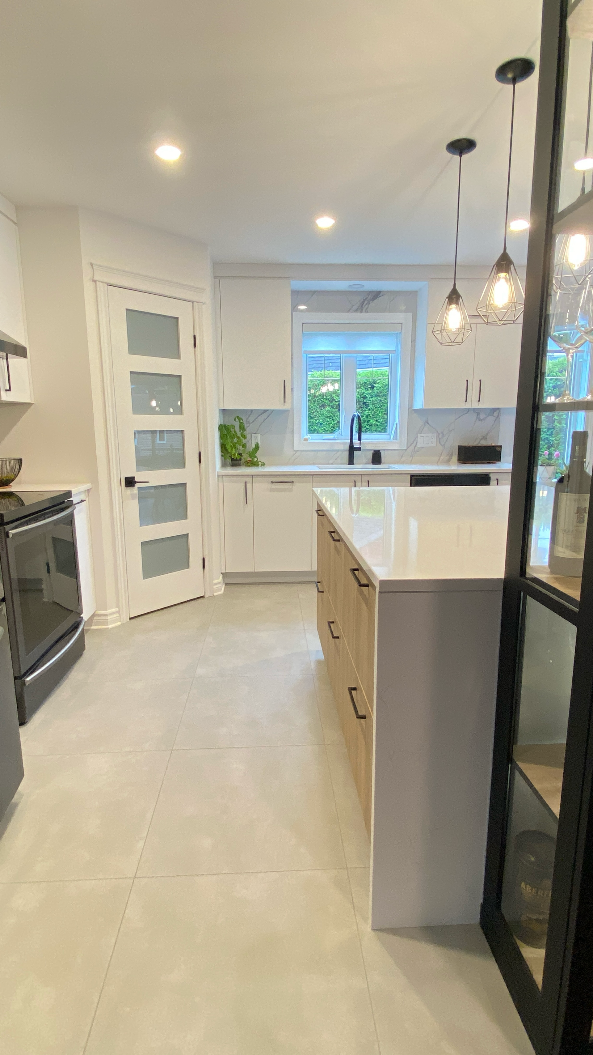 Cuisine moderne avec placards blancs, îlot central en bois clair et porte vitrée.