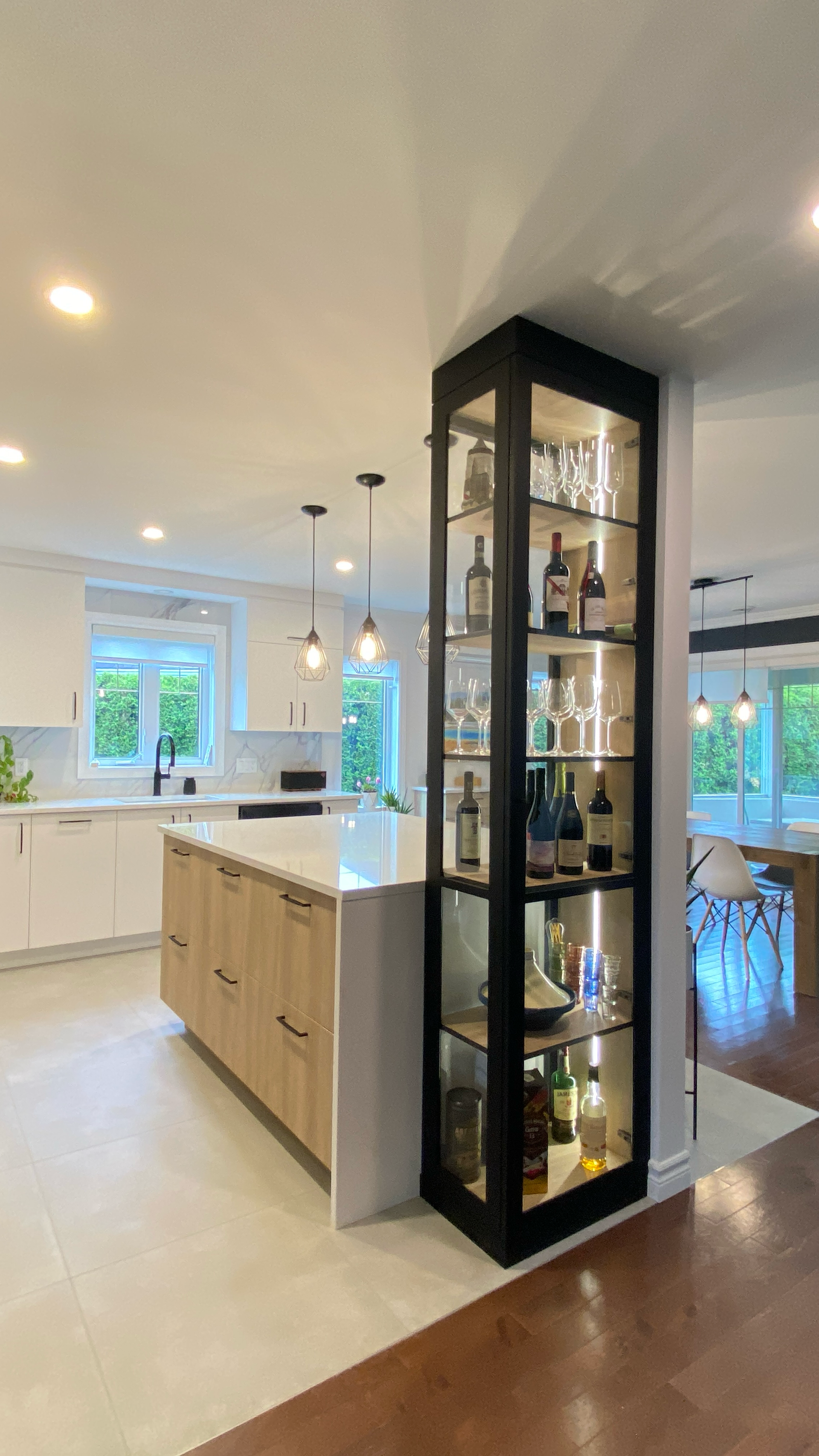 Cuisine moderne avec une vitrine à cadre noir remplie de bouteilles et de verres à alcool.