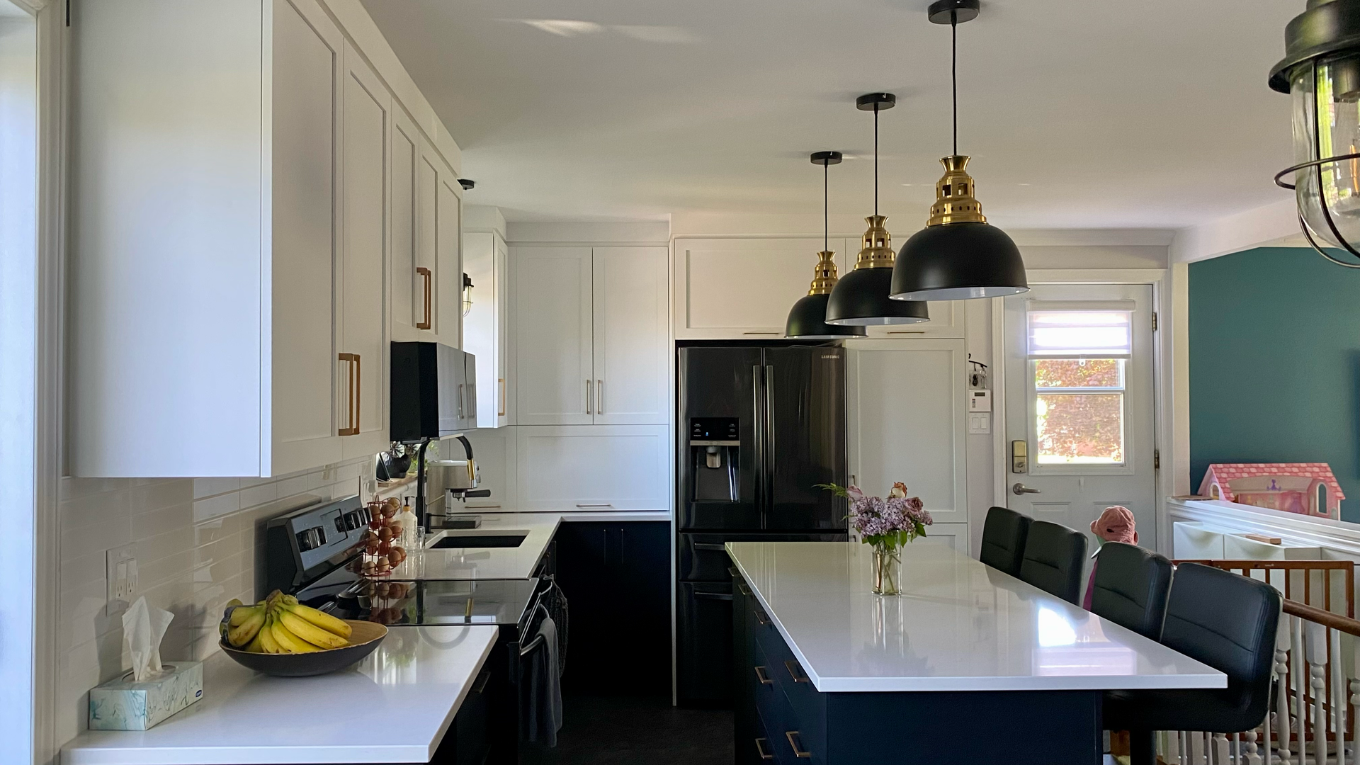 Cuisine moderne avec placards blancs et bleu marine, îlot central avec suspensions lumineuses.