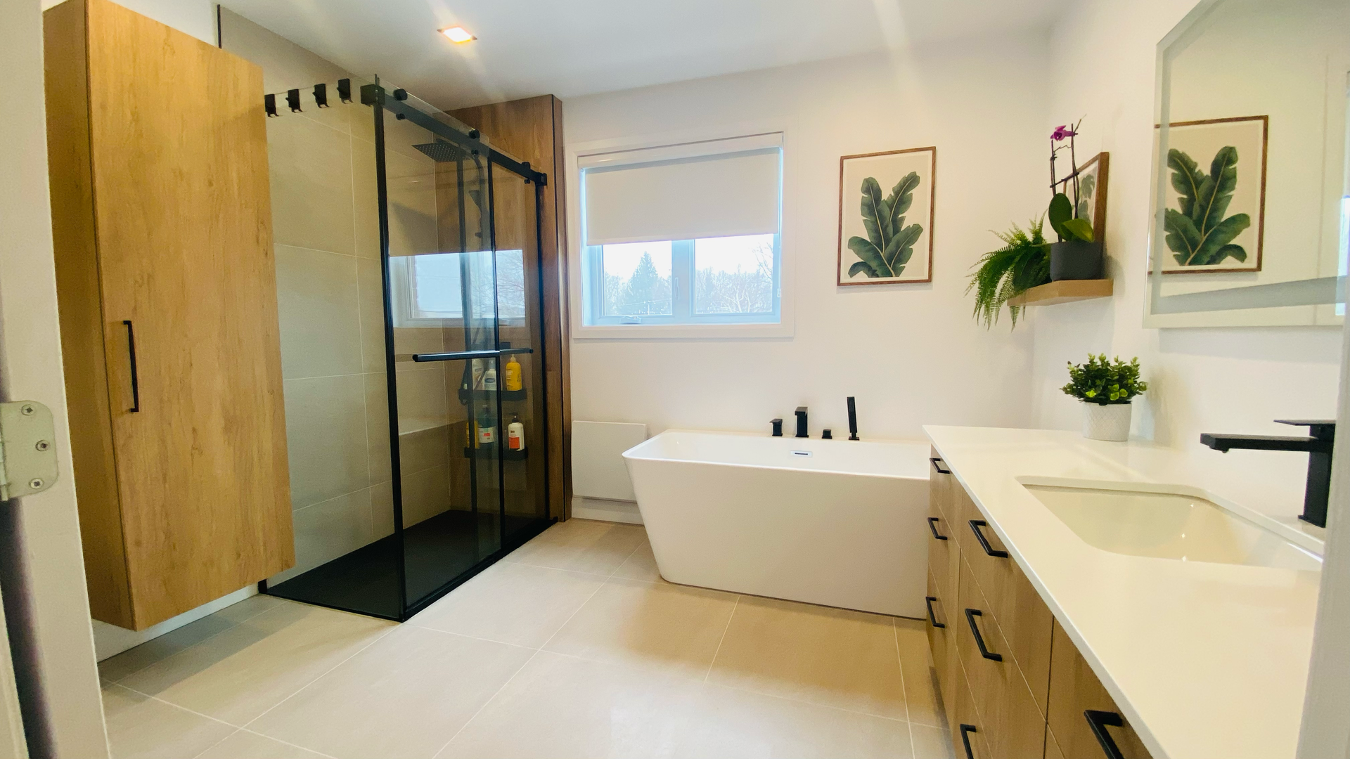 Salle de bains moderne avec meubles en bois, douche en verre, baignoire blanche et meuble-lavabo.