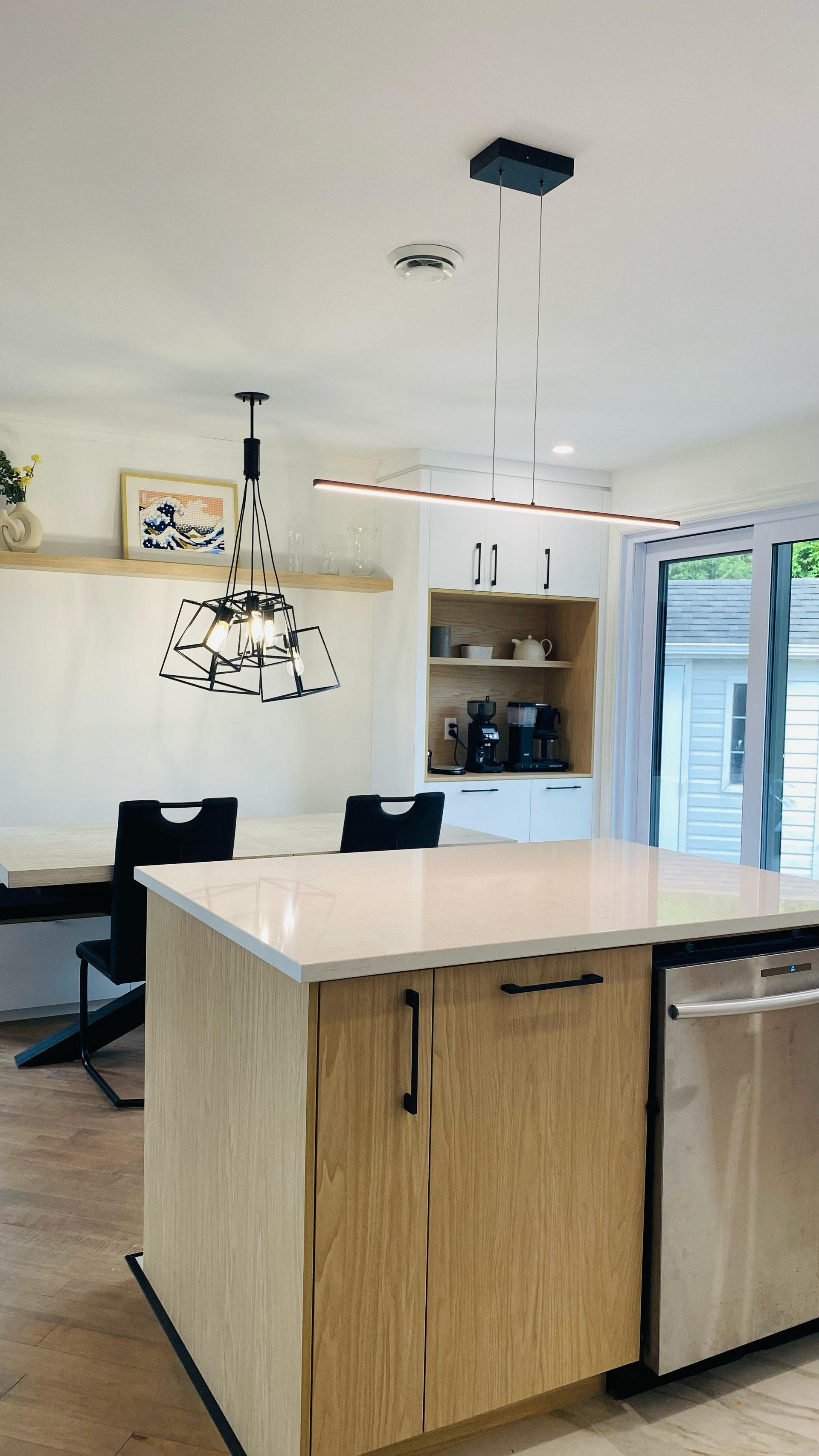 Cuisine moderne avec îlot central, table à manger, luminaires et placard intégré.