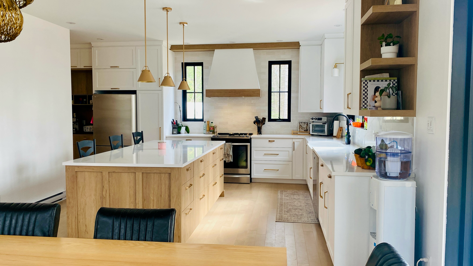 Cuisine moderne avec armoires blanches, îlot en bois et électroménagers en acier inoxydable.