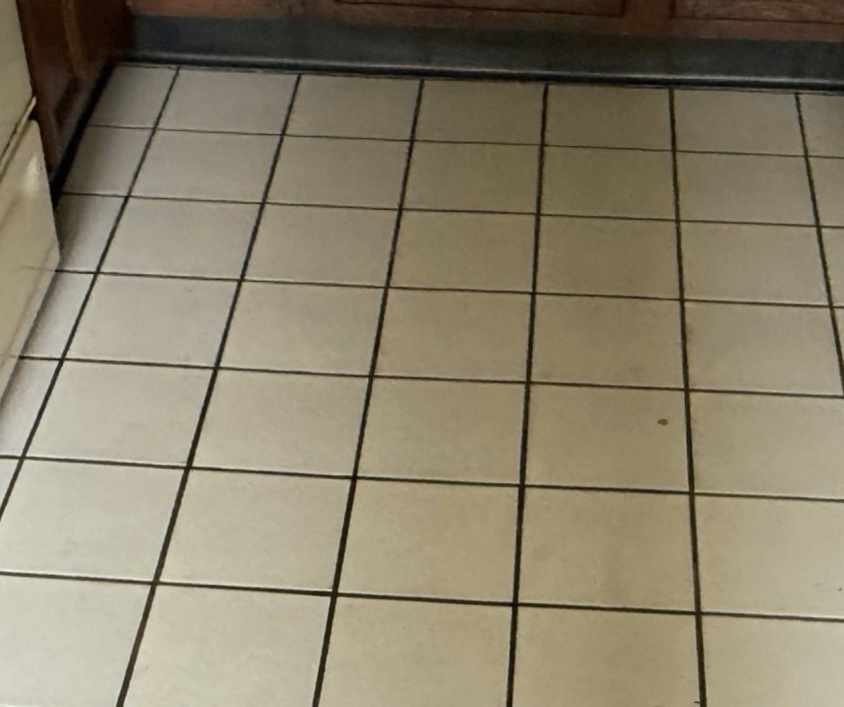Tiled kitchen floor with beige square tiles and dark grout lines, viewed from above