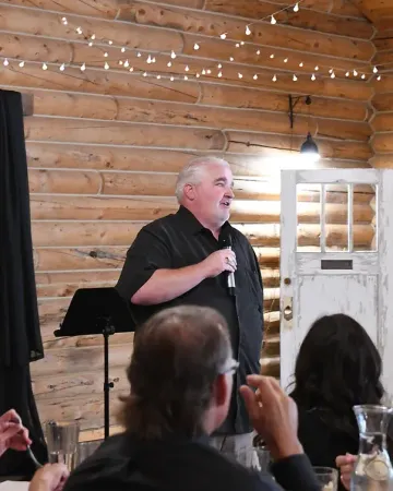A man is speaking into a microphone in front of a group of people