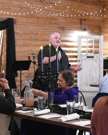 A man is giving a speech to a group of people at a table