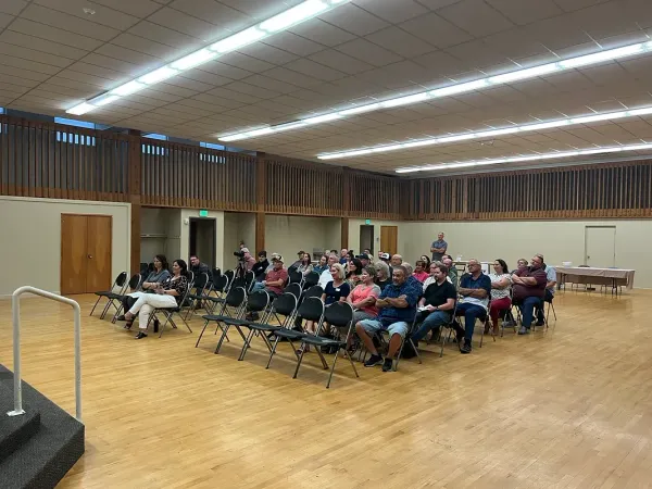 A large group of people are sitting in chairs in a large room.