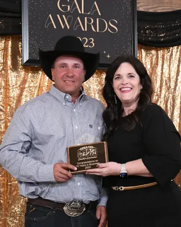 A man and woman are posing for a picture in front of a gala awards sign.