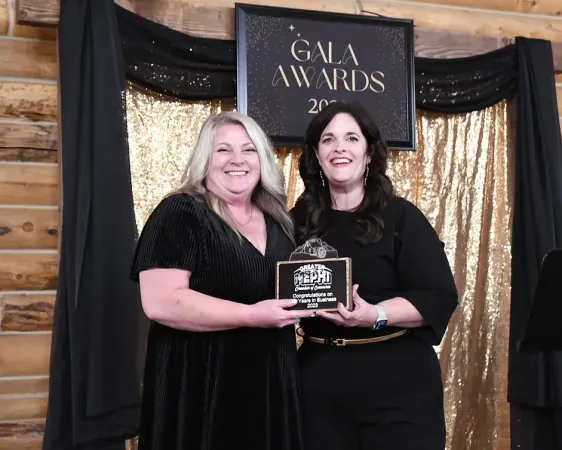 Two women are standing next to each other in front of a sign that says gala awards.
