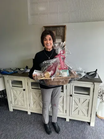 A woman is holding a gift basket in a living room.