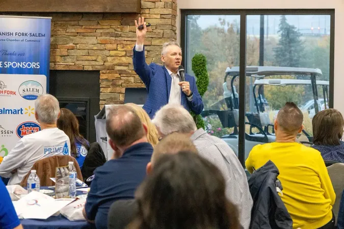 A man is giving a speech to a group of people sitting at tables.