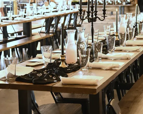 A long wooden table with glasses and candles on it