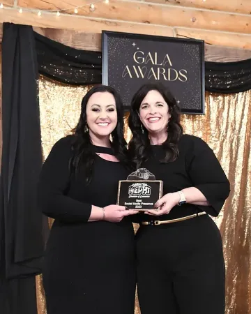 Two women are standing next to each other in front of a sign that says gala awards.