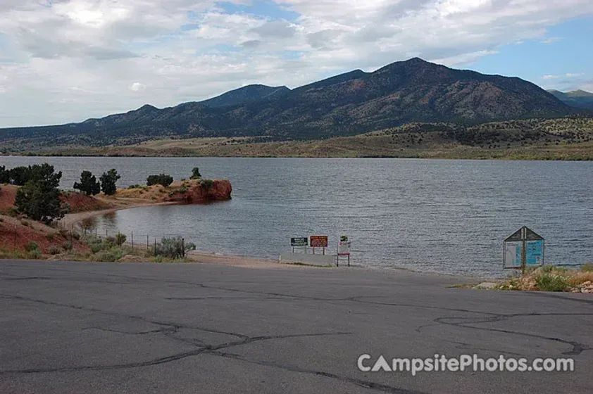A lake with mountains in the background and a road in the foreground.