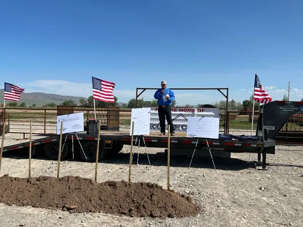 A man is standing on a stage in front of a trailer with american flags.