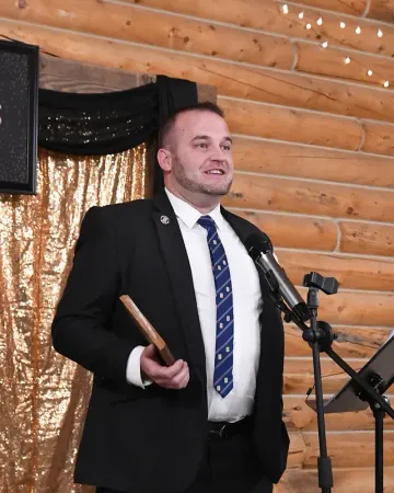 A man in a suit and tie is speaking into a microphone
