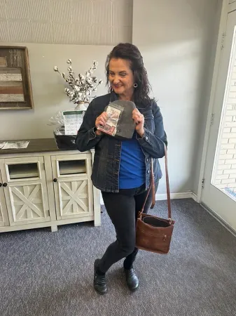 A woman is standing in a room holding a bag of money.