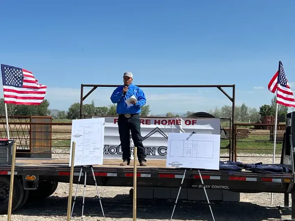 A man is standing on a stage in front of an american flag.