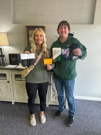 A man and a woman are standing next to each other in a living room holding cards.