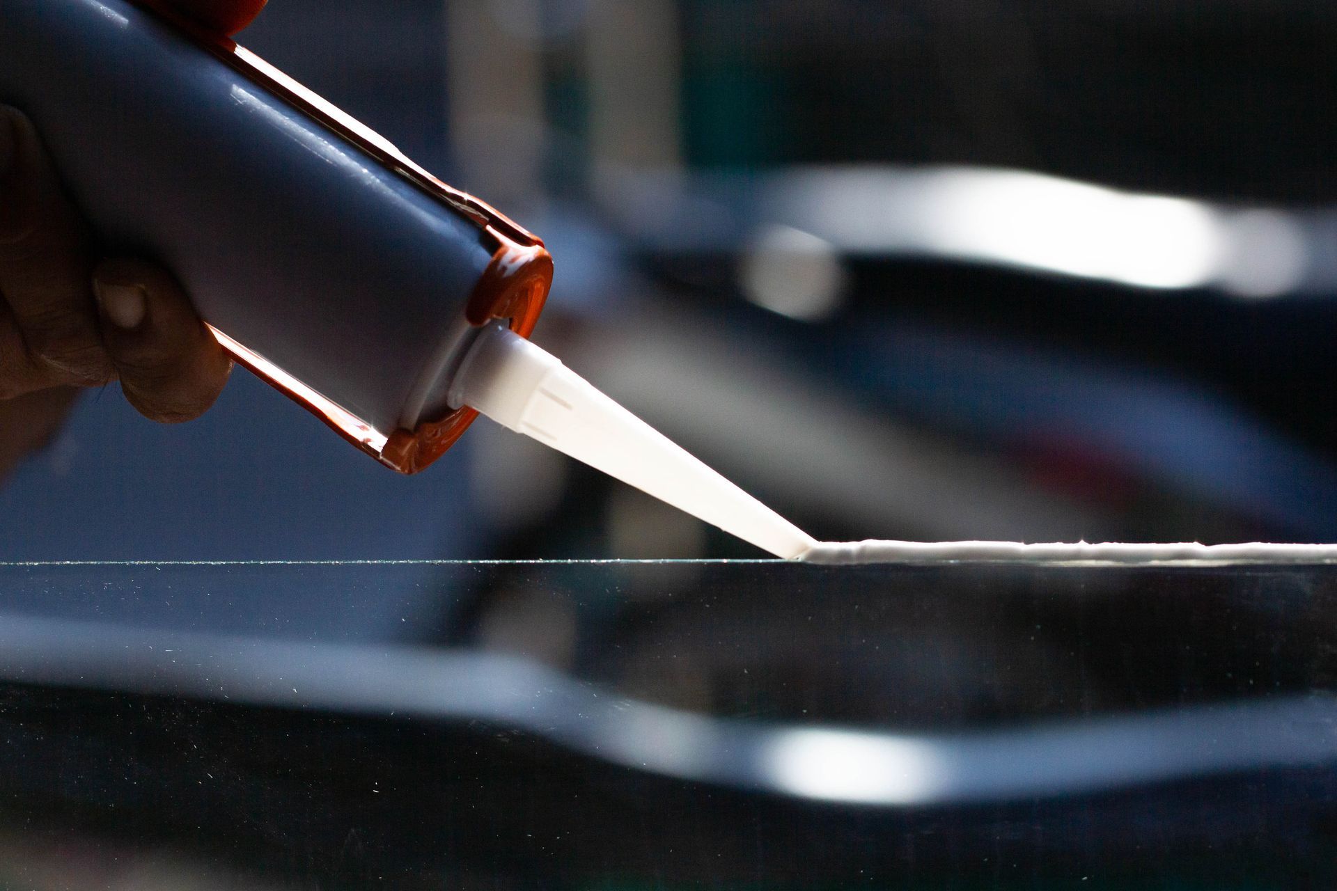 Una persona sta applicando del silicone su un pezzo di vetro.